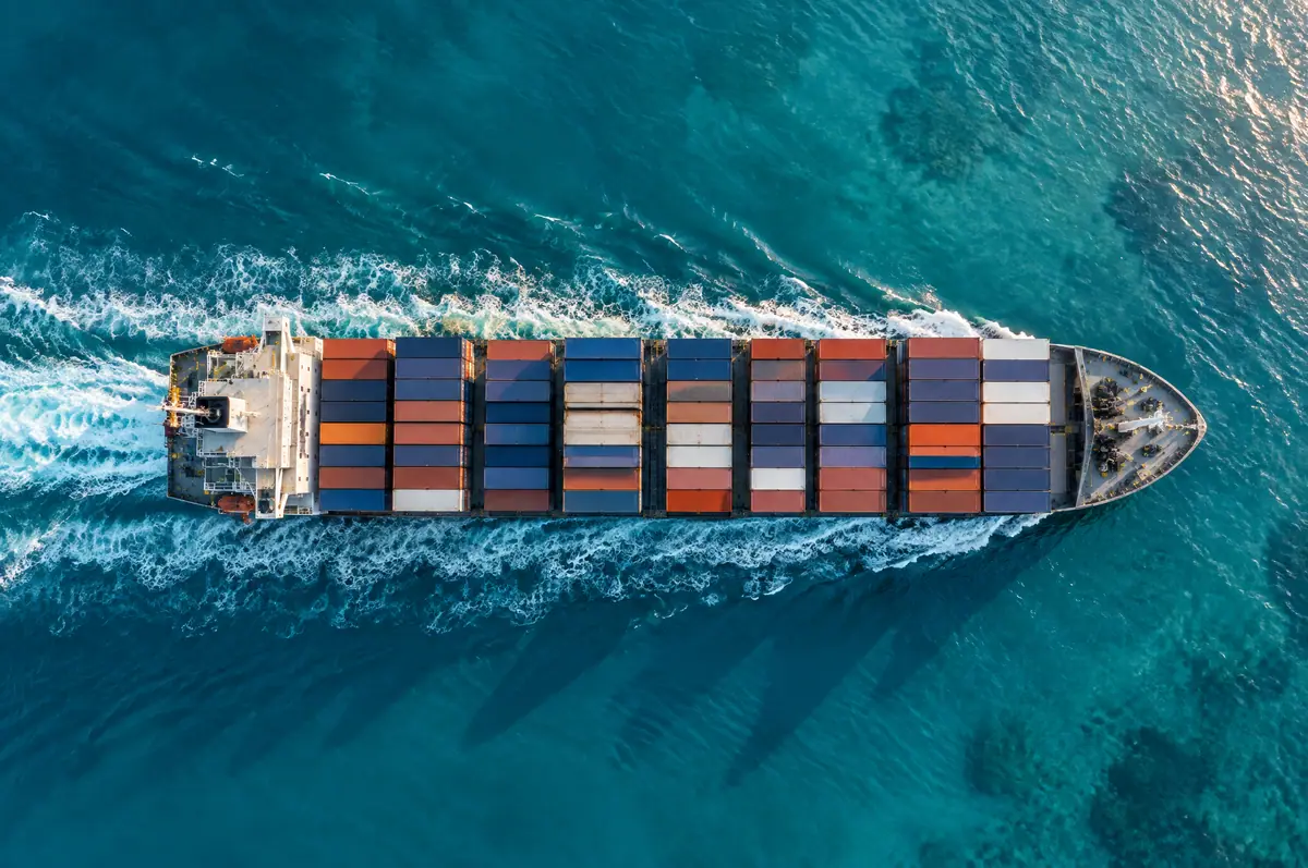 Container ship sailing through turquoise Gulf water, seen from above